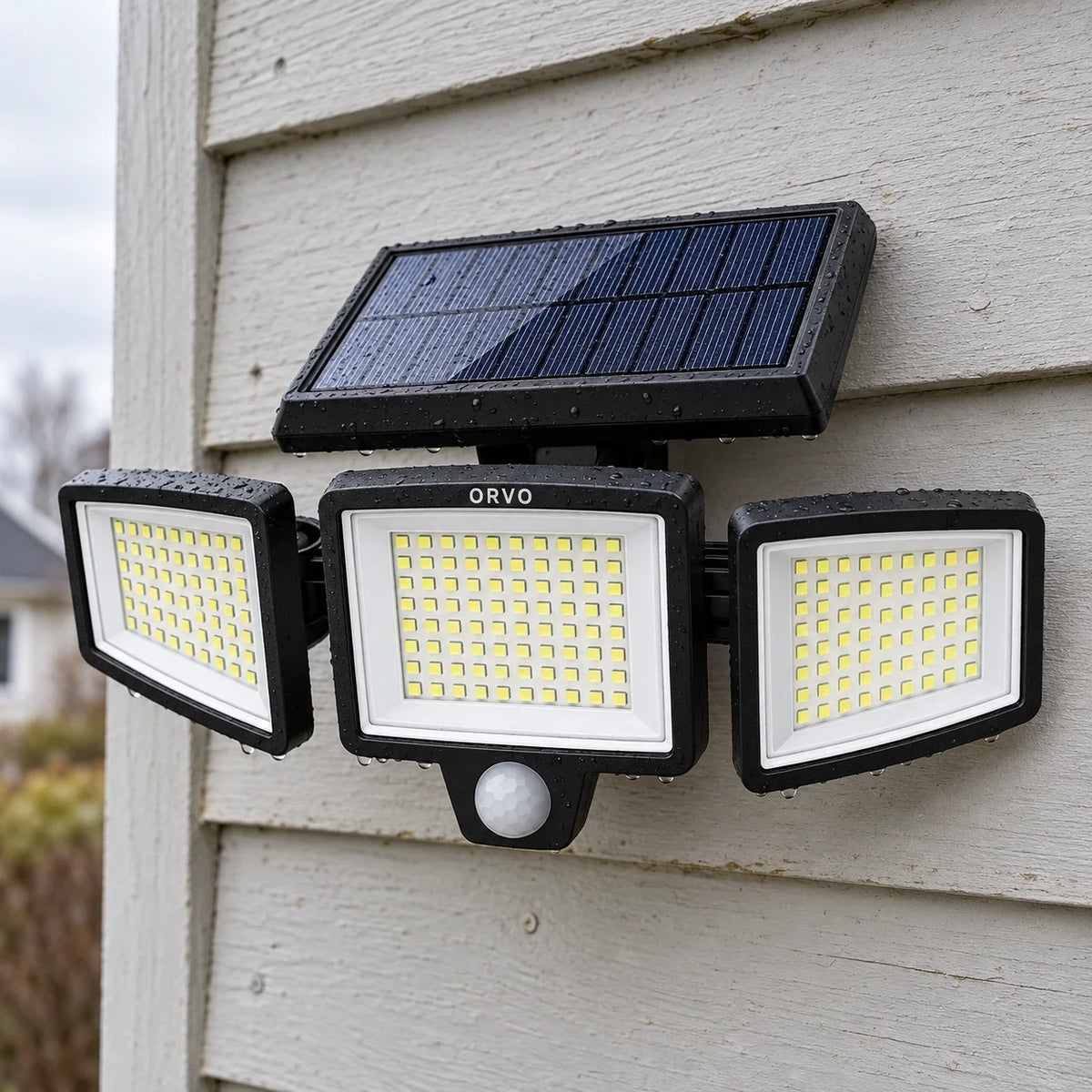 Orvo solar light with three heads lit above a garage door at dusk, a man wheeling his bike inside
